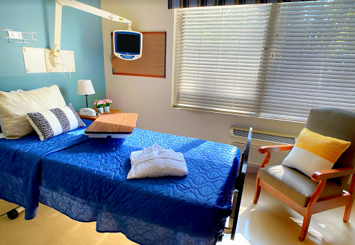 A bright and inviting hospital patient room with a neatly made bed and comfortable seating.