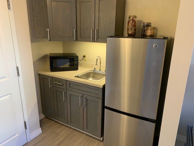Small kitchen area with a fridge, microwave, and sink.