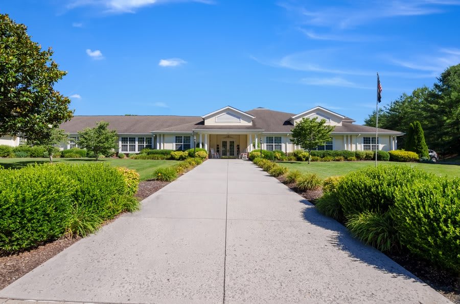 A modern building with a landscaped pathway leading to the entrance under a clear blue sky.