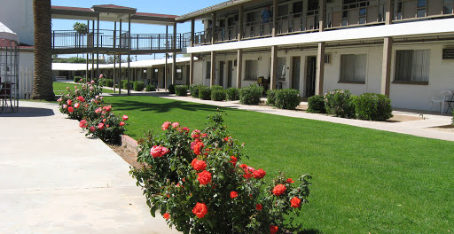 A scenic view of a motel with blooming red roses in the foreground and well-maintained grassy areas.