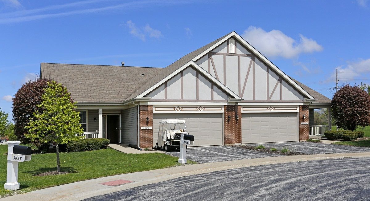 A suburban residential house with a double garage and a driveway on a sunny day.
