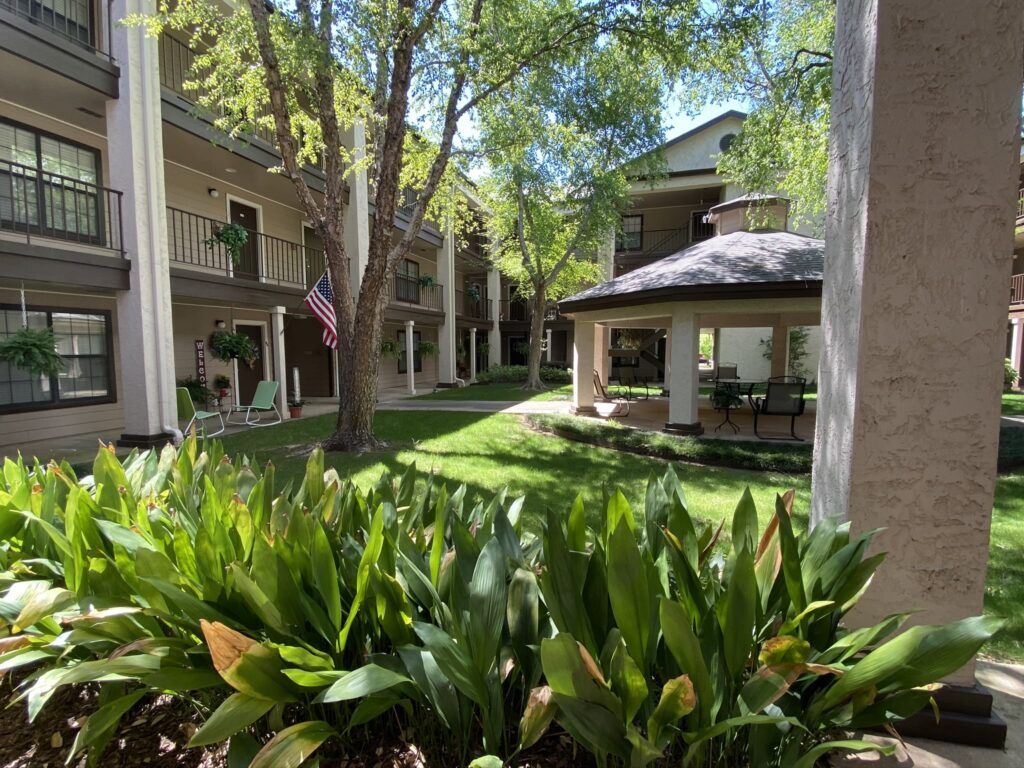 A serene apartment complex courtyard surrounded by lush greenery and trees.