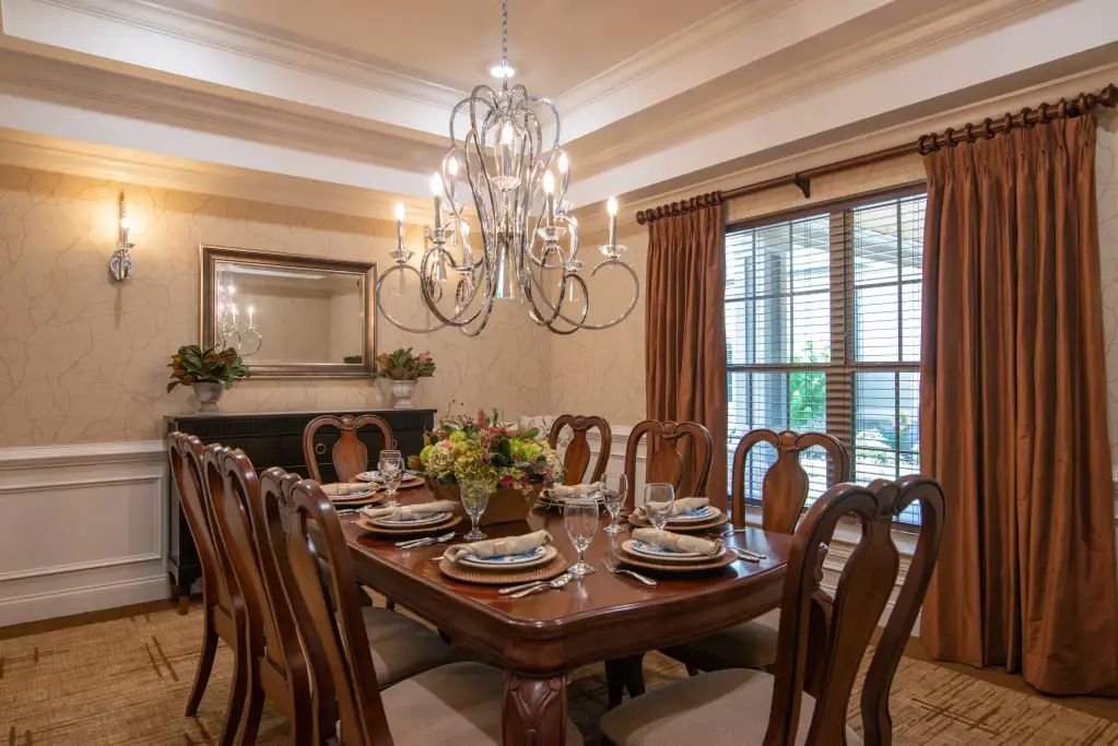 A beautifully arranged dining room featuring an elegant chandelier and a large wooden table set for a meal.