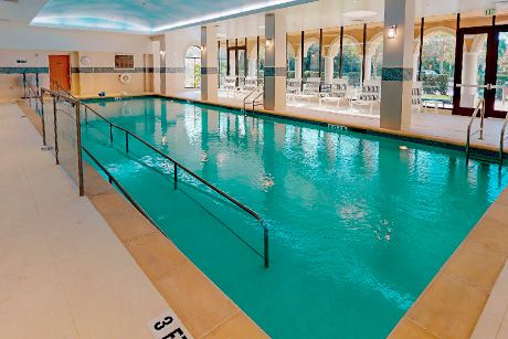 An inviting indoor swimming pool with lounge chairs and natural light.