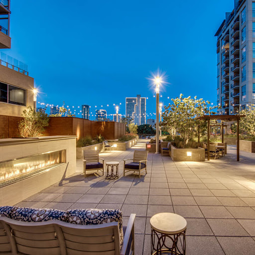 A beautifully lit outdoor patio area in the city, showcasing modern design against a twilight sky.