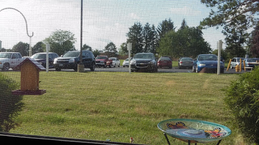 A view of a parking lot filled with cars, surrounded by grass and trees on a sunny day.
