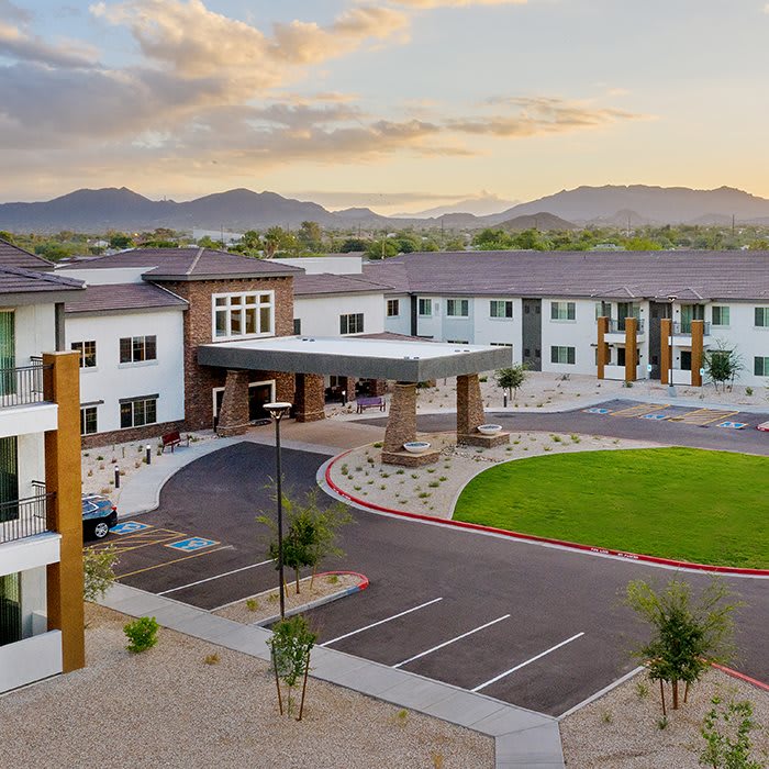 Modern building with a circular driveway set against a mountainous backdrop.