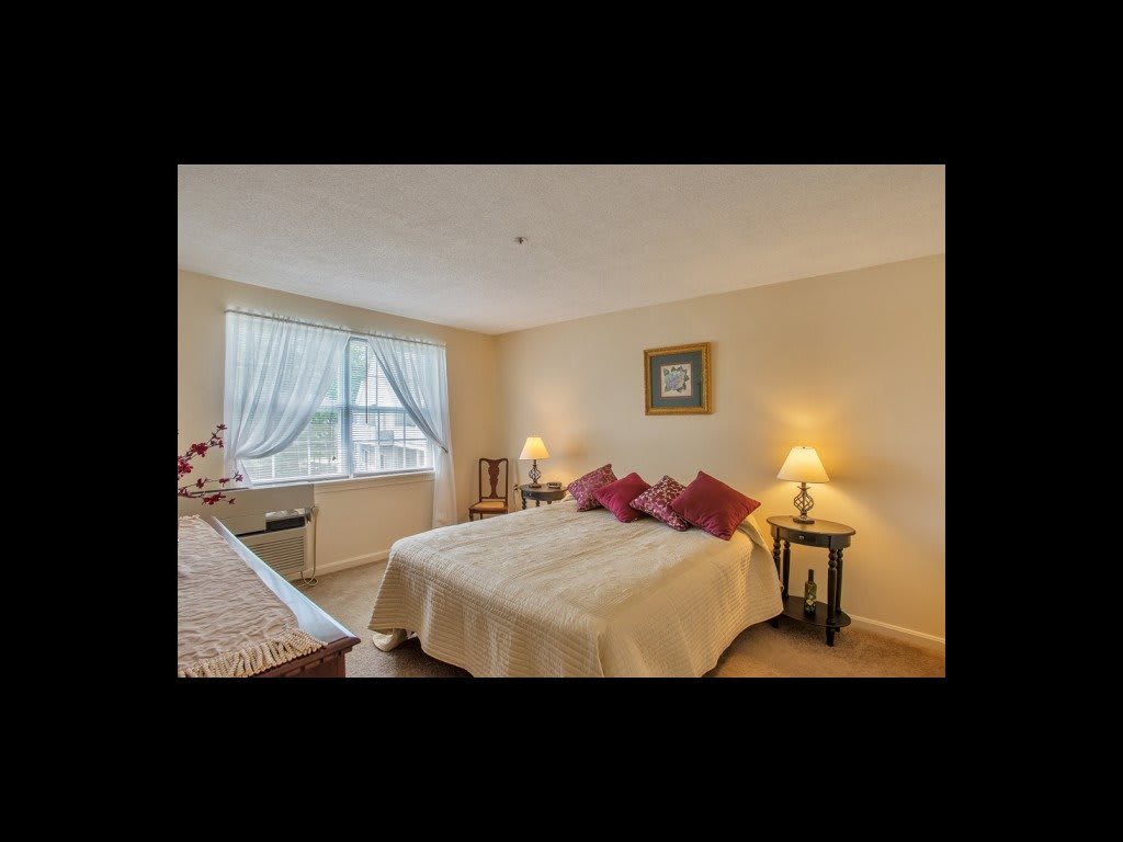 Cozy bedroom with a neatly made bed, nightstands, and soft lighting.