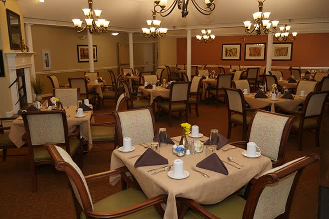 A well-arranged dining room with neatly set tables and elegant chandeliers.