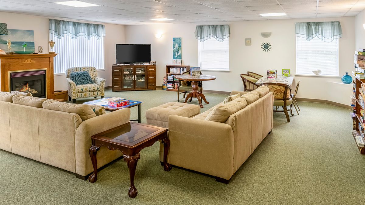 A cozy living room featuring a beige sofa, a coffee table, and a television, with comfortable seating arrangements and various decorative elements.