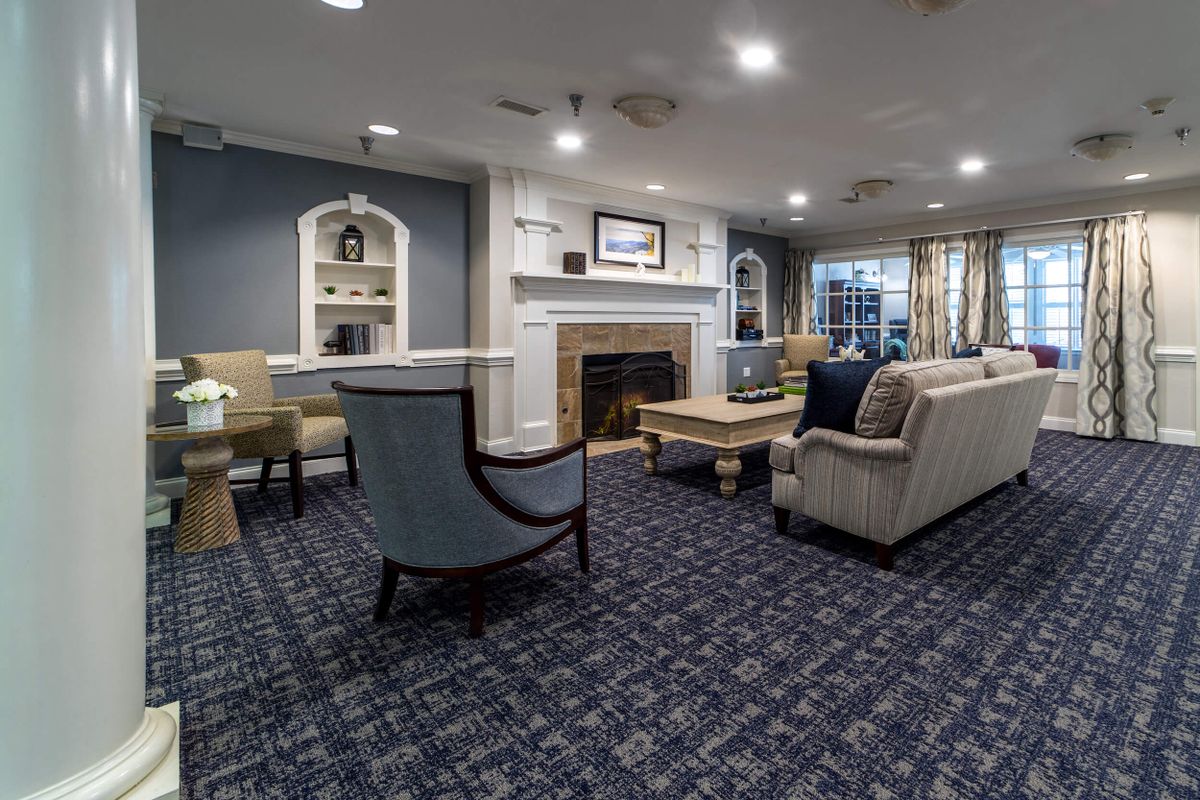 A cozy living room with elegant furniture, featuring a fireplace and a carpeted floor.