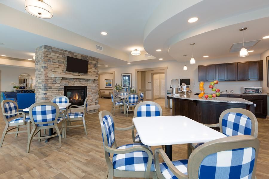 A modern dining area with blue checkered chairs, a fireplace, and a kitchen section.