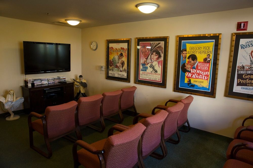 A cozy home theater setup with several chairs facing a television, adorned with classic movie posters on the walls.