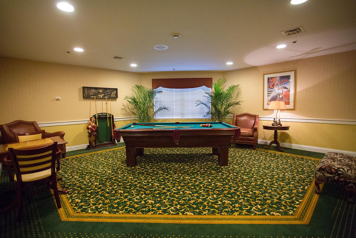 A cozy recreation room featuring a pool table, elegant carpet, and comfortable seating.