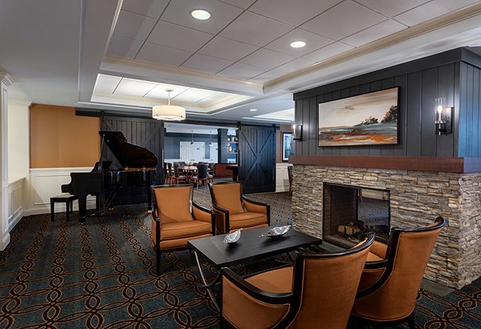 A modern lounge area featuring a fireplace, a grand piano, and comfortable seating.