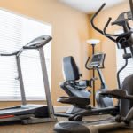 A small gym featuring a treadmill, stationary bike, and elliptical machine.
