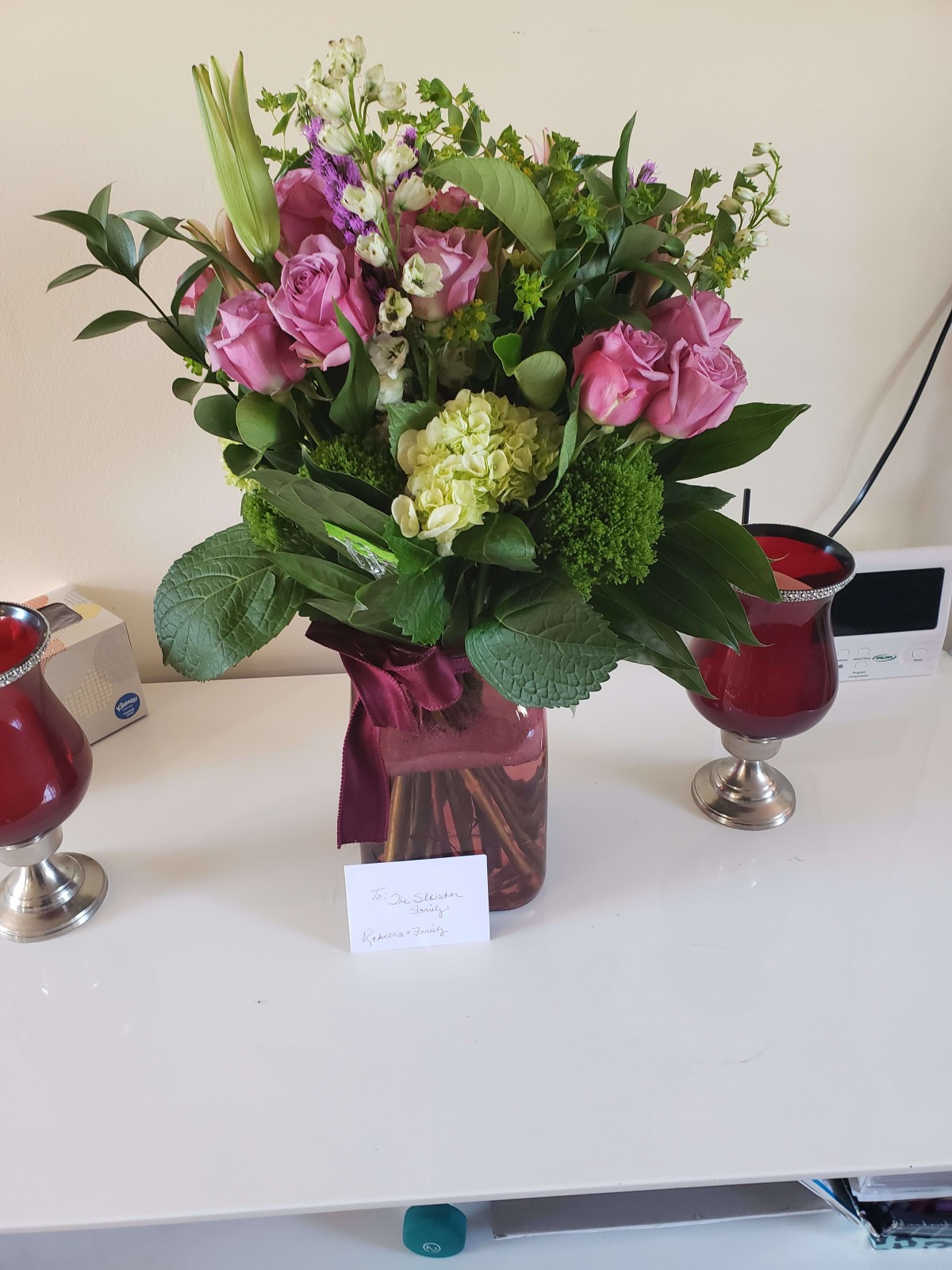 A vibrant bouquet of flowers in a vase, accompanied by two decorative candles on a table.