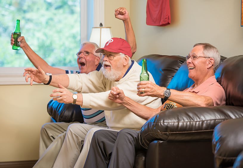 A group of friends enthusiastically watching a game on television in the living room.