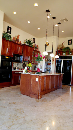 A spacious and modern kitchen featuring elegant wooden cabinetry, a central island, and decorative plants.