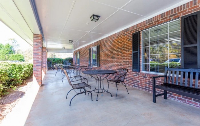 A covered patio with tables and chairs lined up against a brick wall.