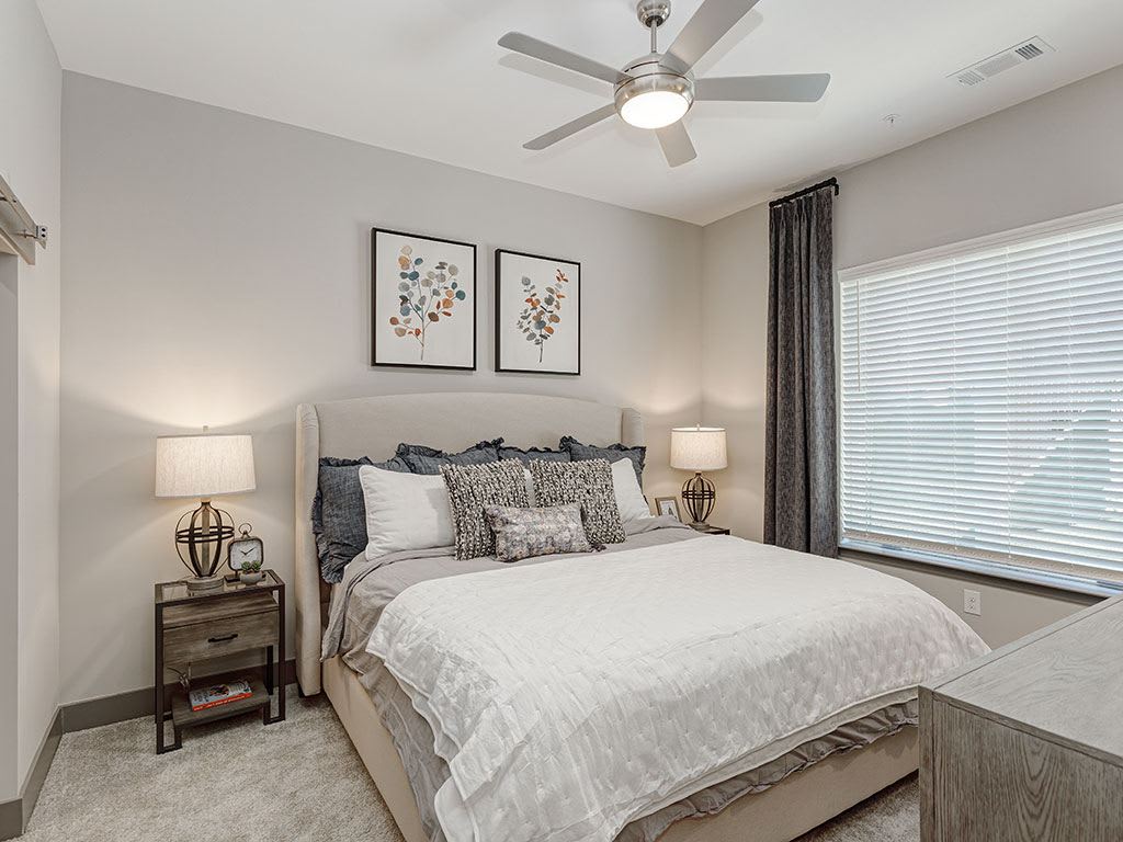 A modern bedroom with elegant decor featuring a comfortable bed, stylish lamps, and framed artwork.