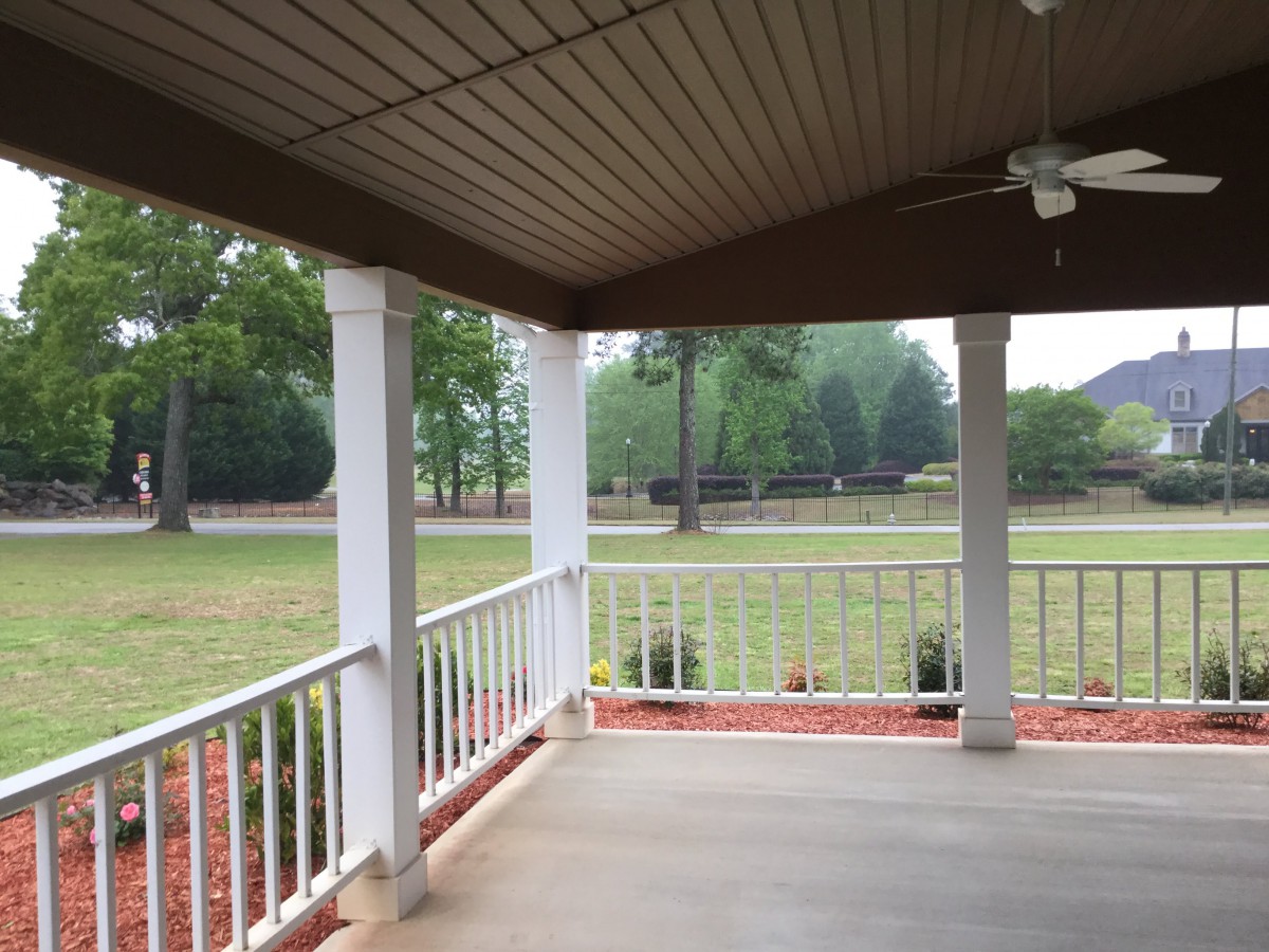 A spacious porch overlooking a green lawn with trees.