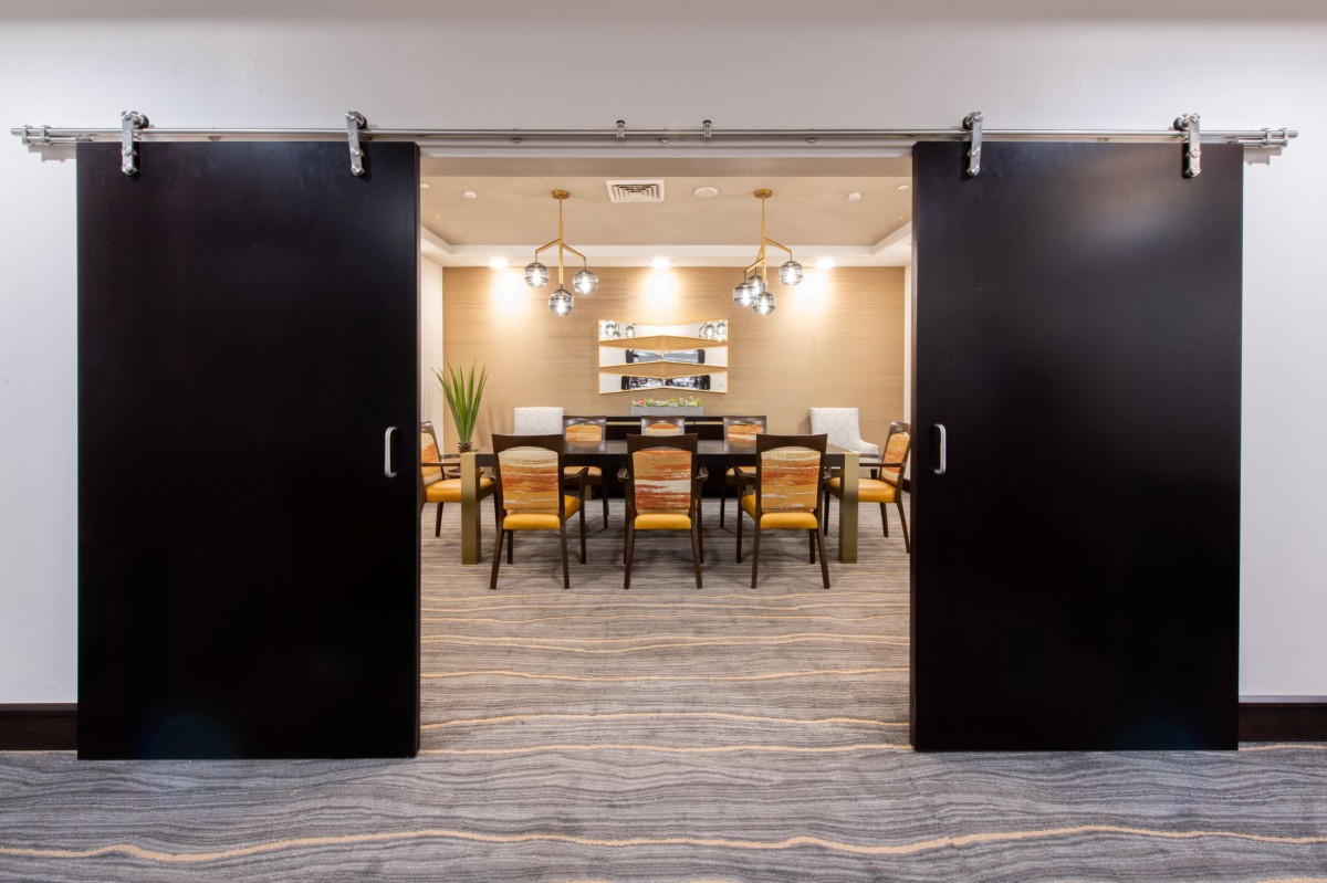 A modern conference room with a long table and chairs, set up for a meeting.