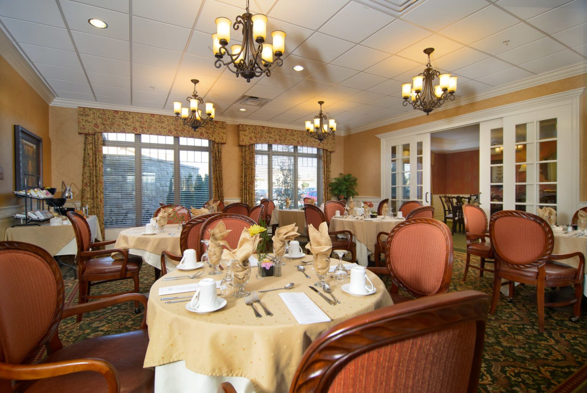An elegant dining room with beautifully set tables and ornate chandeliers.