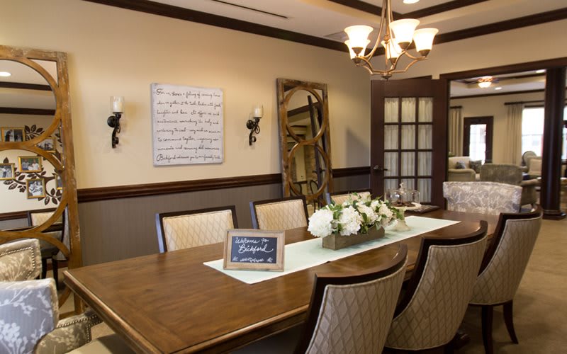 A well-decorated dining room with a large wooden table, elegant chairs, a chandelier, and tasteful wall decorations.