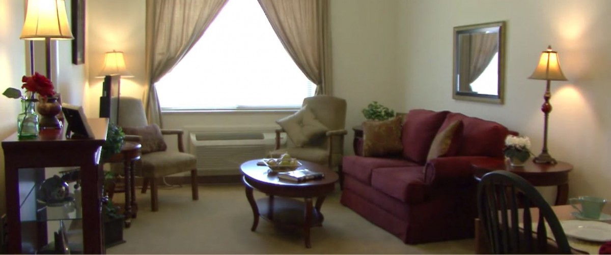 A cozy living room with a sofa, two chairs, and a coffee table near a window with curtains.