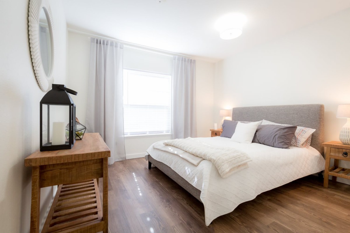A modern, minimalist bedroom with cozy furnishings and abundant natural light.