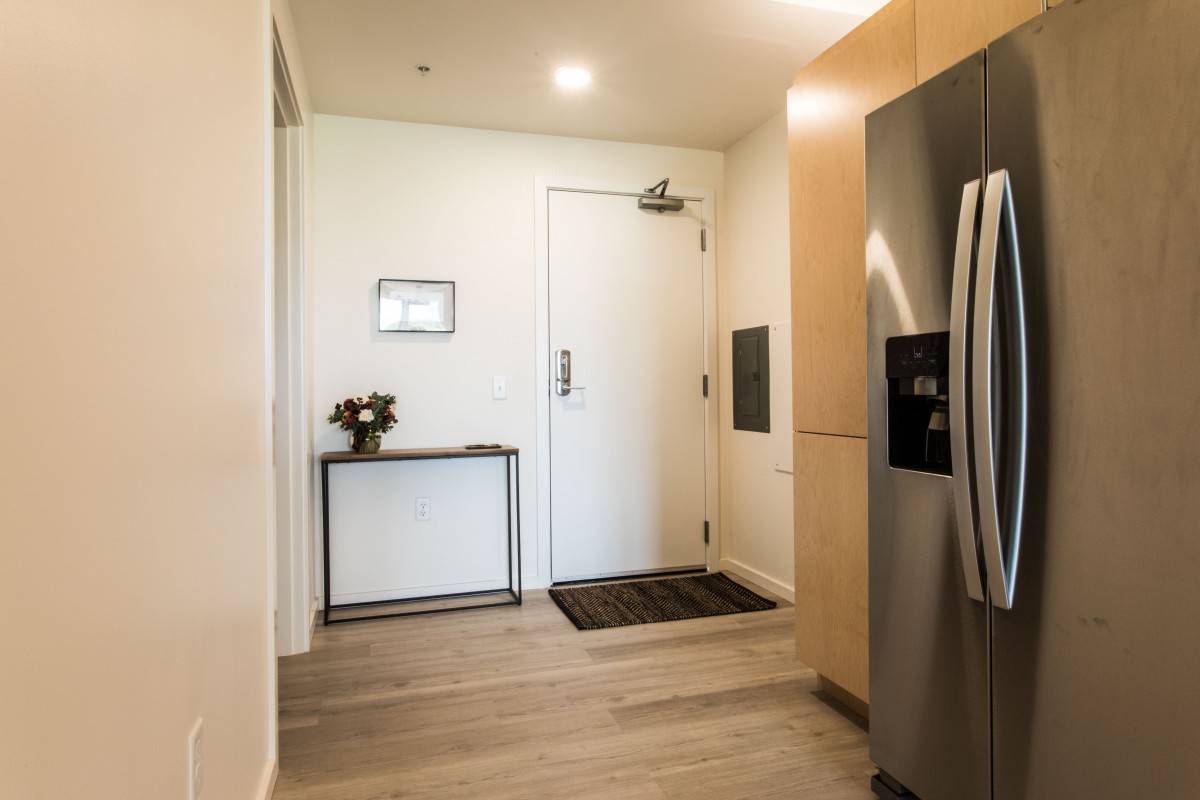 A modern, minimalist entryway with a sleek door, small table, and decor accents.