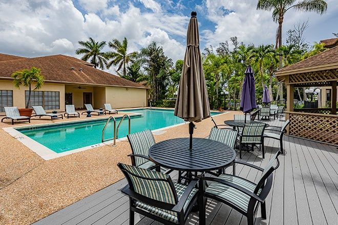 A serene outdoor pool area with surrounding patio furniture and palm trees.