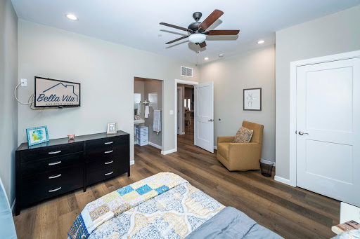 A cozy and well-designed bedroom featuring a comfortable bed, a ceiling fan, and stylish wooden flooring.