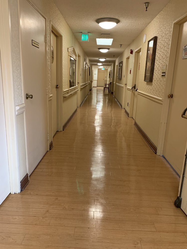 A clean, well-lit hospital corridor with several doors along the hallway.
