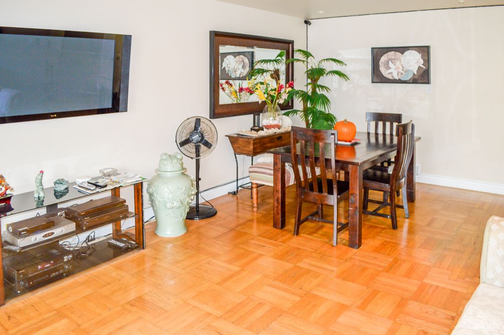 A cozy dining room with wooden furniture, decorated with plants and artwork.