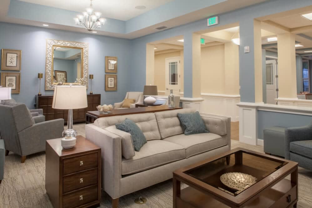 A modern living room with blue walls, featuring a sofa, coffee table, and elegant lighting.