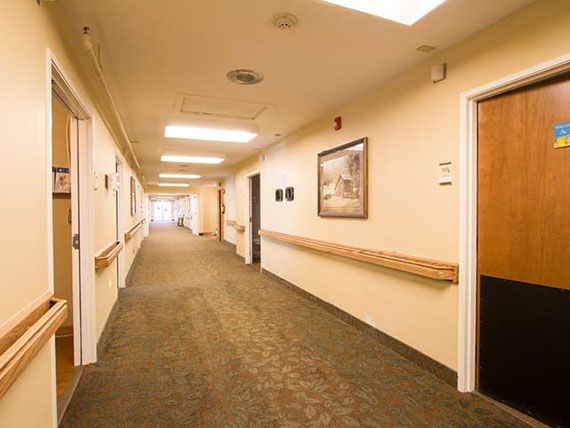 A well-lit hallway with carpet and framed pictures on the walls.
