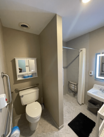 A modern bathroom featuring a toilet, sink, and shower with a neutral color scheme.
