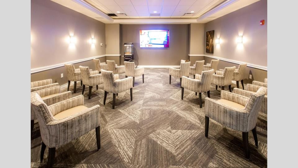 A modern conference room equipped with comfortable seating and a presentation screen.