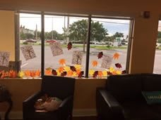 A room with fall-themed decorations on the window, featuring colorful leaves and artwork.