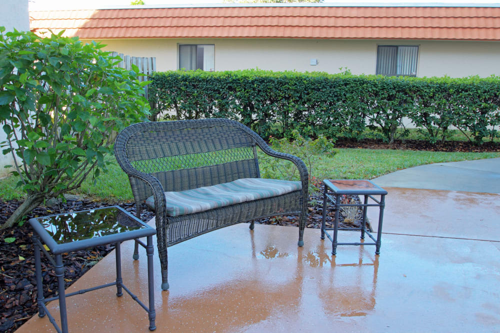 A peaceful patio setting with a bench and tables surrounded by greenery.