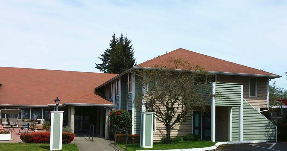 A suburban residential house with a red roof and surrounding greenery.