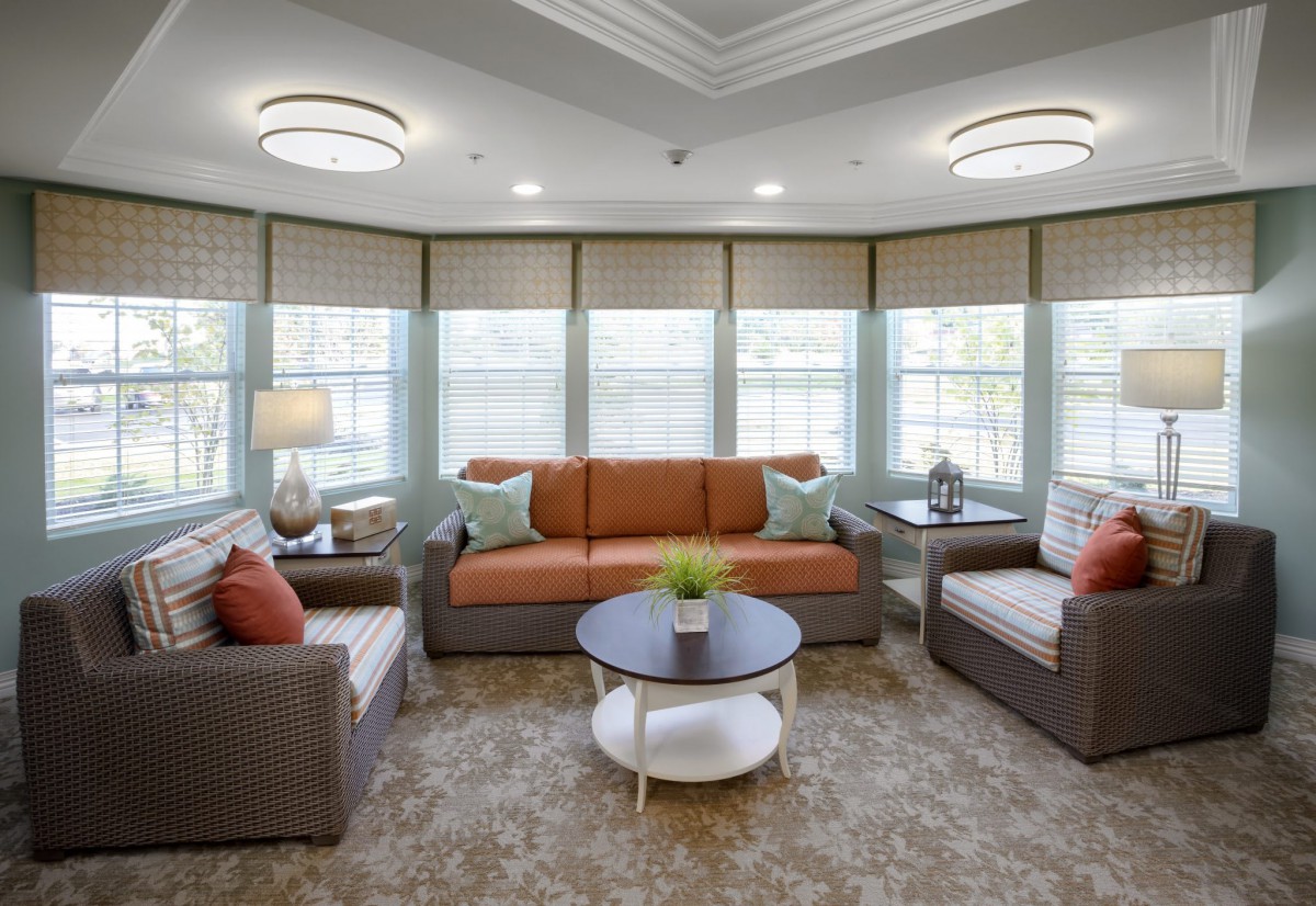 A cozy living room with a sofa, armchairs, and a coffee table surrounded by windows.
