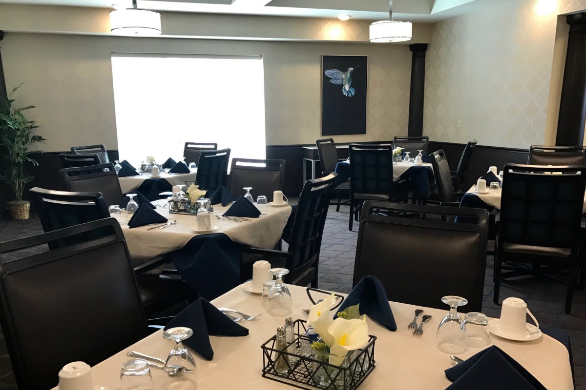 A well-arranged dining area with elegantly set tables and chairs, ready for guests.