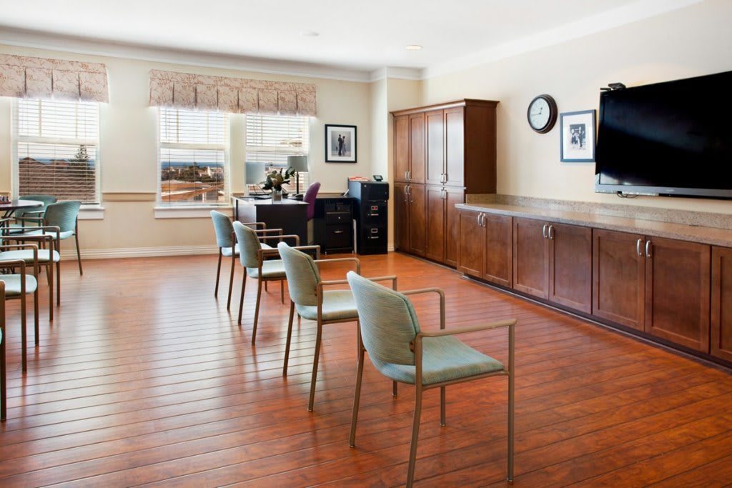 A spacious room with a wooden floor, featuring several chairs and office furniture.