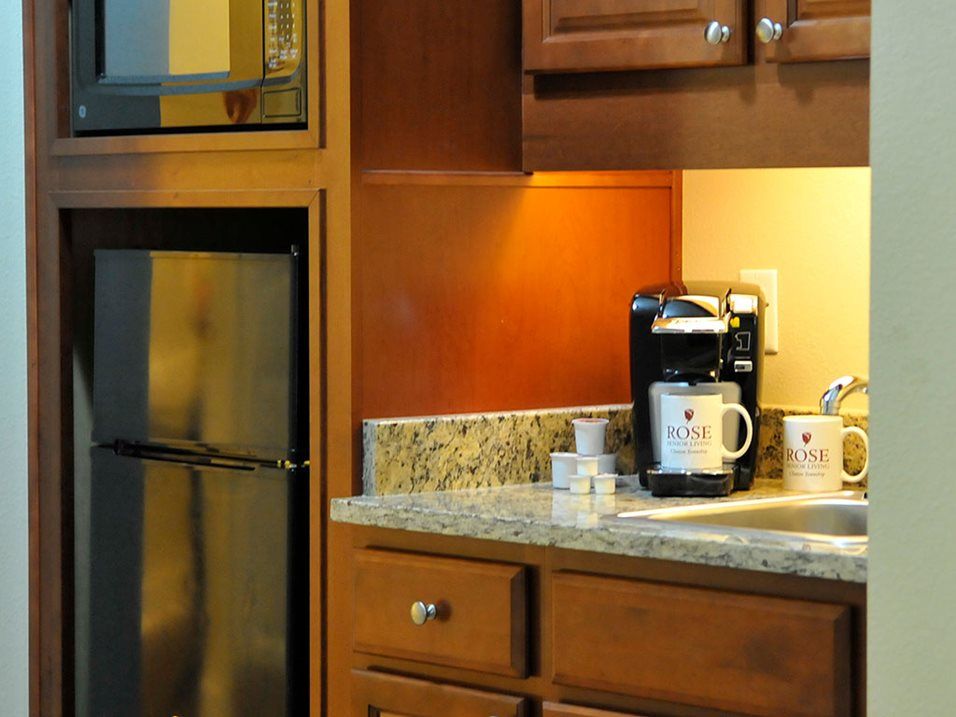 A kitchen counter with a coffee maker and mugs beside wooden cabinets.