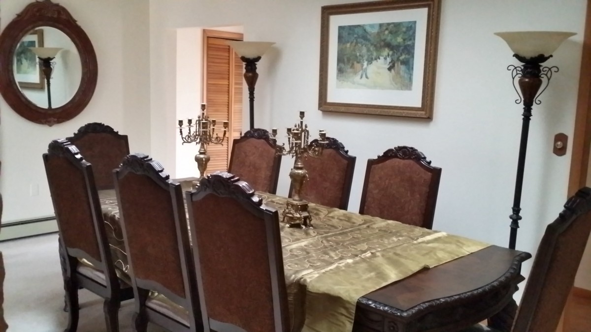 Elegant dining room with a table set for six, adorned with candelabras and artwork on the wall.