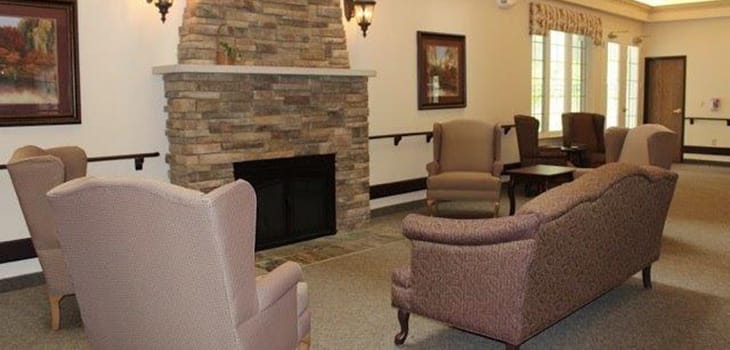 A cozy living room interior featuring a stone fireplace and comfortable seating.