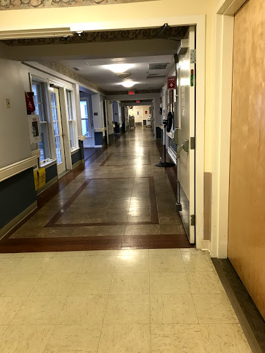 An empty hallway in a healthcare facility, showcasing well-lit interiors and doors along the corridor.